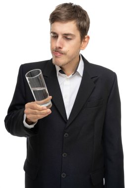 Siyah ceketli, kahverengi saçlı, uzun boylu, zayıf beyaz bir adam beyaz arka planda izole edilmiş bir şekilde bir bardak su tutuyor.