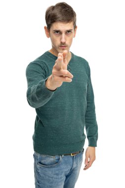 Genç yakışıklı, uzun boylu, zayıf, kahverengi saçlı, beyaz arka planda izole edilmiş koyu yeşil kazaklı, el tabancası jestli adam.