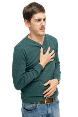 Genç yakışıklı, uzun boylu, zayıf, kahverengi saçlı, kalp krizi geçiren, koyu yeşil kazaklı, beyaz arka planda izole edilmiş kot pantolonlu bir adam.