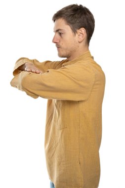 Genç yakışıklı, uzun boylu, zayıf, kahverengi saçlı, kolları çapraz beyaz adam beyaz arka planda yalıtılmış, koyu renk gömlekli.