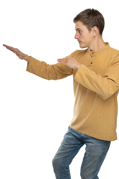 年轻英俊 体形瘦小 一头棕色头发的男子 身穿深褐色衬衫 侧身站在太极上 穿着蓝色牛仔裤 背景为白色 — 图库照片