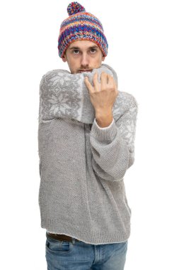Genç yakışıklı, uzun boylu, zayıf, kahverengi saçlı, dirseğini gri kazaklı, beyaz arka planda izole edilmiş kış şapkalı adam.