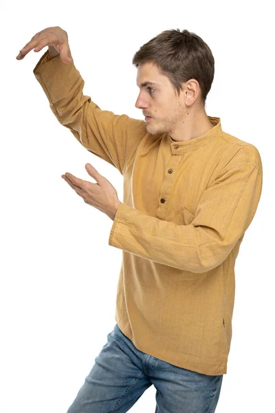 年轻英俊 体形瘦小 一头棕色头发的男子 身穿深褐色衬衫 侧身站在太极上 穿着蓝色牛仔裤 背景为白色 — 图库照片