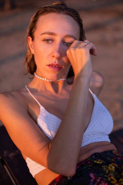 Günbatımında arka planda kum olan Avrupalı genç bir kadının portresi