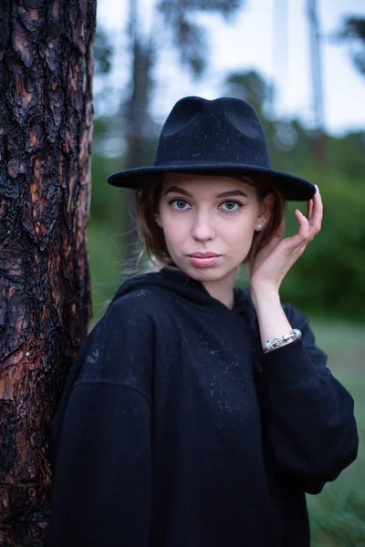 一位身穿深色衣服的年轻白人妇女站在森林里的树上 — 图库照片