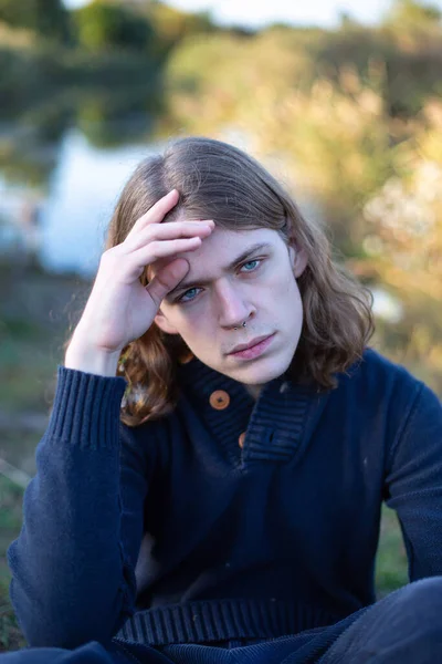 青い目の後ろに湖と長い髪を持つ若いヨーロッパの男 — ストック写真