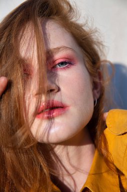 Duvarın yanında parlak makyajlı bir kız.