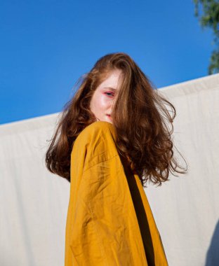 Yüzünün önünde saçları olan parlak makyajlı beyaz bir kız.