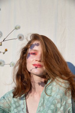 Genç Avrupalı beyaz kız. Koyu saçlı, çiçekli portresi var.