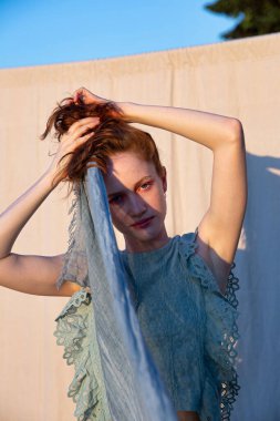 Parlak makyajlı, kızıl saçlarını tutan Avrupalı genç kız.