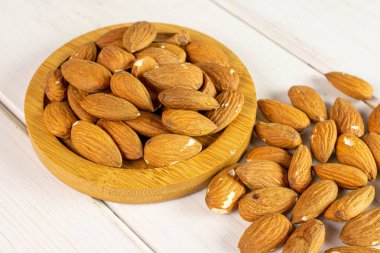 Bir sürü badem beyaz ahşap üzerinde bambu altlığı