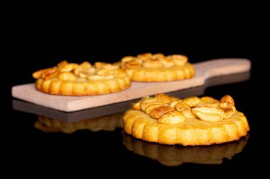 Üç lezzetli kurabiyeden oluşan bir grup. Küçük tahta kesme tahtasının üzerinde yer fıstığı ve siyah cam.