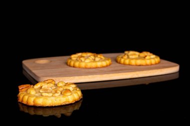 Üç lezzetli kurabiyeden oluşan bir grup. Siyah camlı bambu kesme tahtasının üzerinde fıstık var.