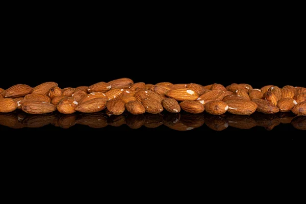 Lot of whole almond in row on black glass