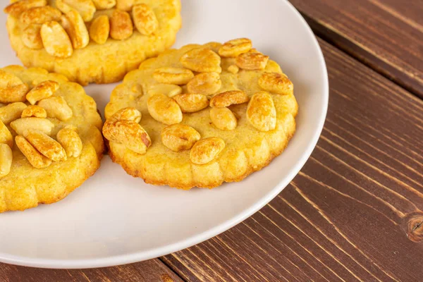 茶色の木の上に白いセラミックプレート上のピーナッツと3つの全体のおいしいクッキーのグループ — ストック写真