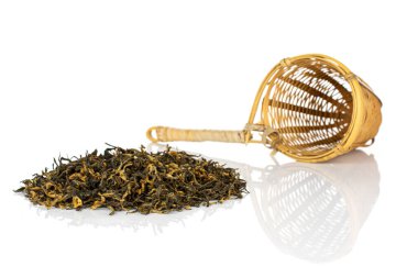 Beyaz arka planda izole edilmiş bambu süzgeci ile kuru siyah çay yaprakları.