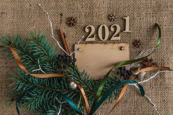 new year and christmas composition, greeting wooden card on a burlap background, stylish. Flat lay, copy space, top view