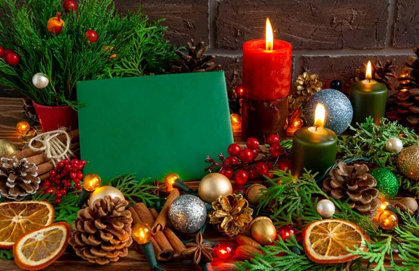 Composição atmosférica de Natal ou Ano Novo, cartão verde em branco, velas, árvore de natal, guirlanda. Espaço de cópia — Fotografia de Stock