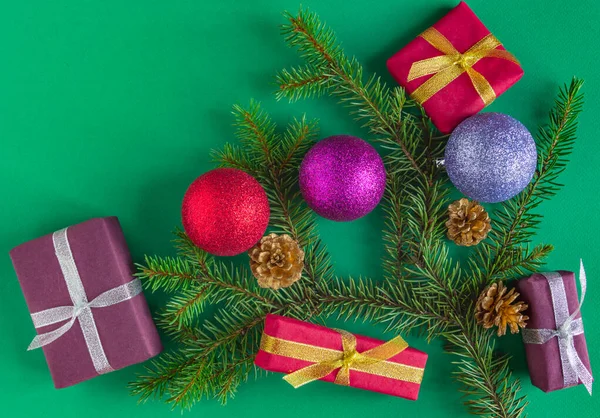 Karácsony, Szilveszter kártya - ajándékok, labdák, lucfenyő, toboz zöld háttérrel. Lapos fekvés, másolás, felülnézet — Stock Fotó