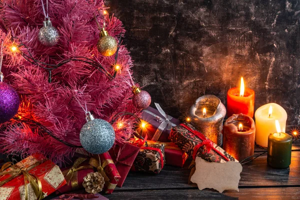 Composição de Natal ou Ano Novo atmosférico, árvore de Natal rosa no fundo preto, velas, presentes. Espaço de cópia — Fotografia de Stock