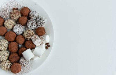 Kakaolu trüf mantarı, hindistan cevizi ve çikolata ve marşmelovlu susam tohumu, beyaz arka planda lezzetli bir tatlı.