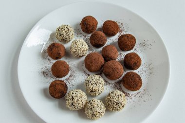 Kakaolu trüf mantarı, hindistan cevizi ve çikolata ve marşmelovlu susam tohumu, beyaz arka planda lezzetli bir tatlı.