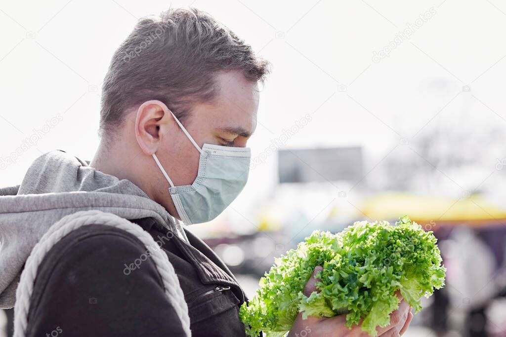 Masked man in the local market buying broccoli cabbage in period of pandemic. Covid Pandemic shopping concept.