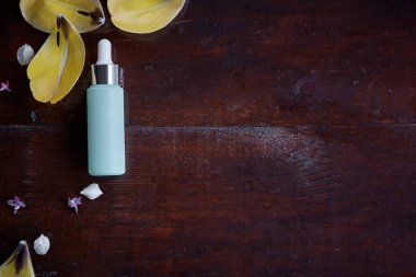 Damlatan cam şişe, Model-up. Kişisel bakım konsepti. Vücut bakımı ve spa. Doğal güzellik ürünleri. Turkuaz anti-yaşlanma serumu düşürücü, sarı lale yapraklı bir şablon. Doğal sağlık.