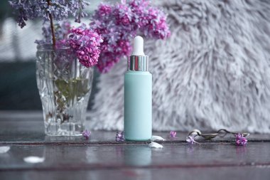 Turkuaz anti yaş serum damlasını leylak çiçekleriyle süsleyin. Doğal sağlık kozmetik ürünü. Damlatan cam şişe maketi. Vücut bakımı ve spa. Doğal güzellik ürünleri. Kişisel bakım kavramı