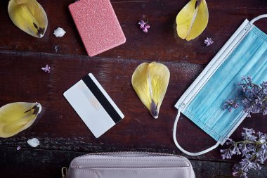 Kadınların debriyaj patlaması maske, ödeme kartı ve bahar çiçekleriyle ayna. Üst Manzara. Zarif kadınsı konsept