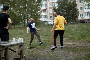 Kyiv, Ukrayna - 15 Mayıs: Gençler bahçede amatör futbol oynuyor. Aktif eğlence. Spor eğlencesi. Ön planda tek kullanımlık gözlükler var..