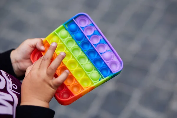 Colorful antistress sensory toy fidget push pop it in kids hands. Antistress trendy pop it toy. Motor skills development. Rainbow sensory fidget. New trendy silicone toy.