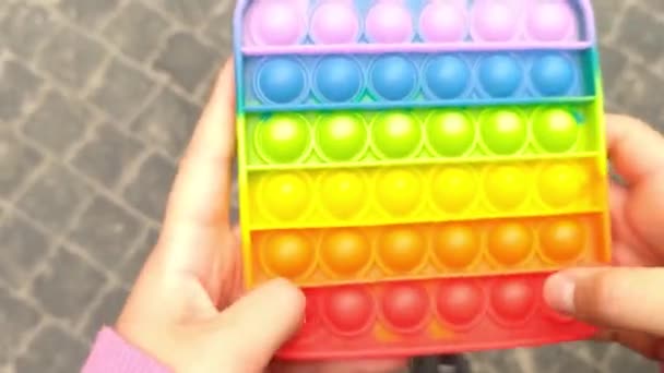 Girls hands push it modern trendy rainbow silicone toy. New trendy wave. Colorful antistress sensory toy fidget push pop it in kids hands. Antistress trendy pop it toy. — Stock Video