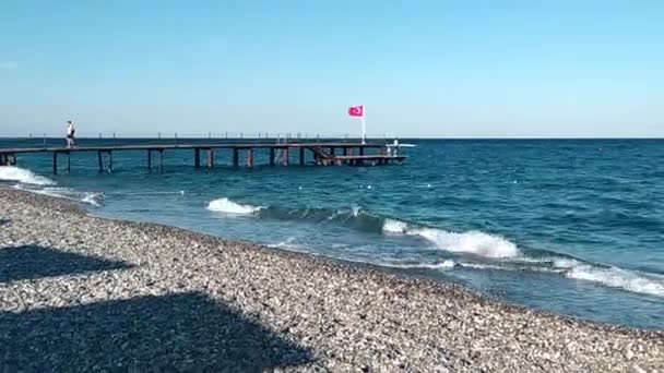 Güneşli bir günde canlı su yüzeyi. Denizde bir iskelede ulusal Türk bayrağı. Güneşli Akdeniz — Stok video