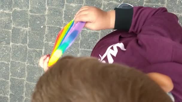 Peuter speelt met regenboog zintuiglijk siliconen speelgoed. Kleurrijke antistress sensorische speelgoed fidget duwen pop het in handen van kinderen. Antistress trendy pop het speelgoed. — Stockvideo