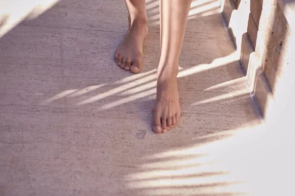Gambe delle donne in ombre alla moda di una palma su parete di pietra naturale beige. Trendy minimale sfondo concreto astratto. Sfondo estivo — Foto Stock