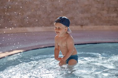 Kafkasyalı şirin bebek yüzer ve küçük havuzda yüzer. Yaz tatili ve eğlence kavramı