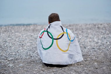 Kemer, Türkiye - 16 Haziran 2021: İnsan deniz kıyısında Olimpiyat bayrağıyla kaplıdır. Olimpiyat oyunları konsepti. Umut ve başarı kavramı. Yüksek kalite fotoğraf