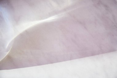 Mermer yüzeyinde doğal güneş ışınları olan zarif bir arka plan. Minimalist moda geçmişi. Seçici odaklanma. Boşluğu kopyala.