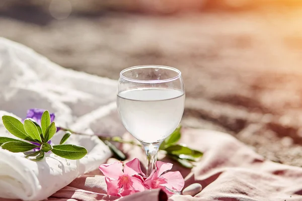Plajda, çiçeklerle ve güneş ışığıyla birlikte şarap kadehinde cin tonik kokteyli. Hassas ipek malzemeler ve bokeh arkaplan. Yaz konsepti tazeleniyor — Stok fotoğraf