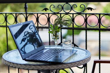 Eller dizüstü bilgisayarda güneşli bir günde terasta serbest çalışır. Yazmak, not almak, webinar izlemek. Kendini soyutlama, ev konseptinde çalışma. Online iş. Yüksek kalite fotoğraf