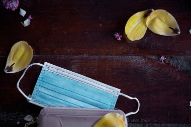 Koronavirüs salgını sırasında koruyucu tıbbi maske. Etrafı lale yapraklarıyla çevrili. Umut ve koruma kavramı. Moda arkaplanı.