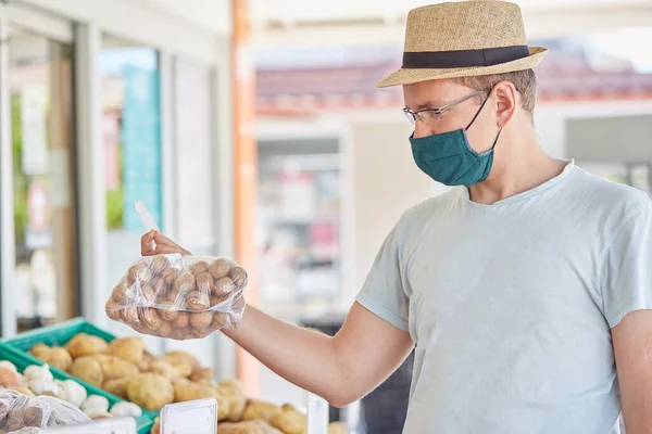 Man in a mask buys vegetables at a street farmer\'s market. Coronavirus quarantine concept. High quality photo