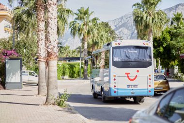 Kemer, Türkiye - 24 Mayıs 2021: Güneşli bir günde TUI seyahat otobüsü, çiçek açan ağaçlar, palmiyeler, yeşil doğa, arabalar, otobüs ve yol tabelaları ile gezinti. Yaşam tarzı editör görüşü. Yüksek kalite fotoğraf