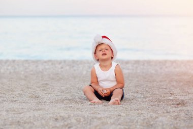 Küçük beyaz çocuk yeni yıl arifesini ya da sahilde Noel 'i kutluyor. Tatil konsepti, Noel havası. Yüksek kalite fotoğraf