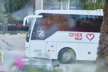 Kemer, Türkiye - 23 Mayıs 2021: Anex tur otobüsü, çiçek açan ağaçlar, palmiyeler, yeşil doğa, gün batımında arabalar. Yaşam tarzı editör görüşü. Yüksek kalite fotoğraf