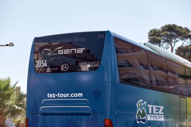 Kemer, Türkiye - 24 Mayıs 2021: TEZ tur otobüsü, güneşli bir günde çiçek açan ağaçlar, palmiyeler, yeşil doğa ve gökyüzü ile gezinti. Yaşam tarzı editör görüşü. Yüksek kalite fotoğraf