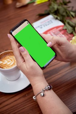 Kadının elinde krom anahtarlı cep telefonu ekranı ve masanın üzerinde bir fincan kahve. Üst Manzara. Eğitim, çalışma, serbest çalışma kavramı. Yüksek kalite fotoğraf