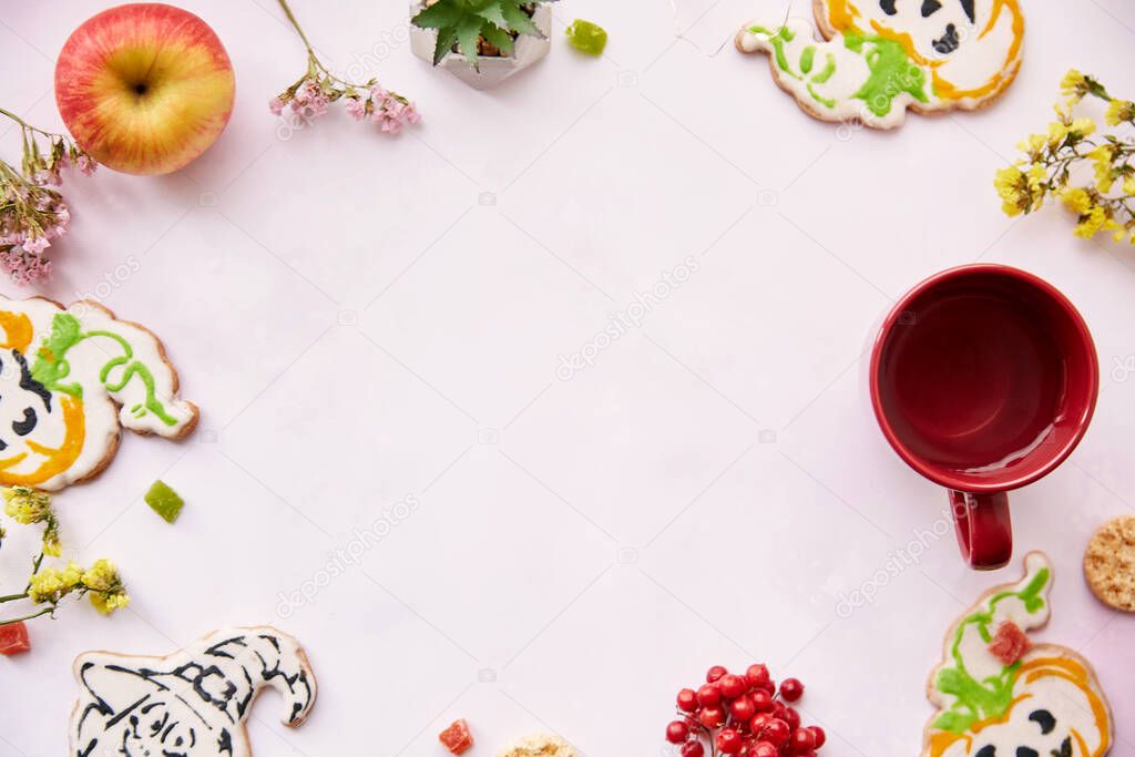 Halloween festive background: red cup, homemade cookies in shape of cute pumpkins and ghost. Atmospheric aesthetic autumn mood or trick or treat concept. Apples, dry flowers, candied fruit. Copy space.