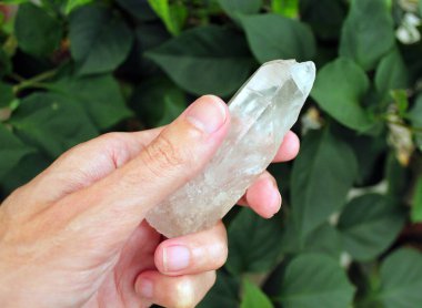 El beyaz bir kristal tutuyor.